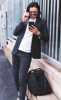 portrait of Young smiling handsome Asian man in semi formal suit using mobile phone photo