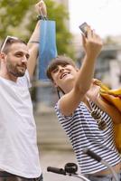 Portrait of cheerful Caucasian young couple man and woman holding many paper bags after shopping while walking and talking on street. Happy family couple with packages outdoor. Buying concept photo