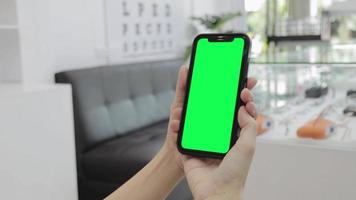 groen scherm, smartphone groen scherm in hand, gebruik groen scherm voor kopiëren ruimte detailopname. chroma sleutel mock-up Aan smartphone in hand. vrouw houdt mobiel telefoon groen scherm video