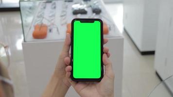 Green screen, smartphone green screen in hand, Use green screen for copy space closeup. Chroma key mock-up on smartphone in hand. Woman holds mobile phone green screen video