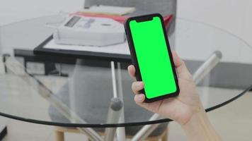 Green screen, smartphone green screen in hand, Use green screen for copy space closeup. Chroma key mock-up on smartphone in hand. Woman holds mobile phone green screen video