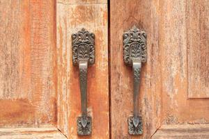 Brown wooden door has a key and a lock and a handle for locking the door to prevent thieves and thieves from stealing your belongings and valuables. It is an ancient wooden door photo