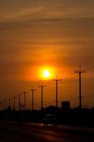 atmosphere in the evening-high voltage pole beside highway and orange sky The big sun that was setting was beautiful as I was on my way home, it was a beautiful romantic atmosphere. photo