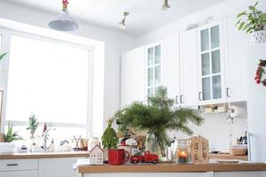 Festive Christmas decor in white kitchen, festive breakfast, white scandi interior. The figure of a cozy house ion the set table. New Year, mood, cozy home. Copy space photo