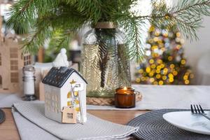 Key to the house on cozy home with Christmas decor on table of festive kitchen. Gift for New Year. Building, design, project, moving to new house, mortgage, rent and purchase real estate