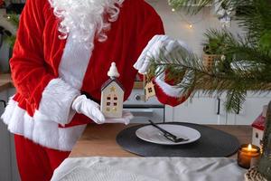 House key with keychain cottage in hands of Santa Claus outdoor in snow. Deal for real estate, purchase, construction, relocation, mortgage. Cozy home. Merry Christmas, new year booking event and hall photo