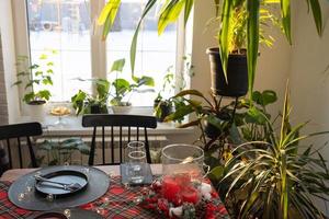 Sunny interior of a loft-style house with potted plants, a large window, a covered table for the Christmas and New Year holidays photo