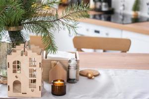 Festive Christmas decor in white kitchen, festive breakfast, white scandi interior. The figure of a cozy house ion the set table. New Year, mood, cozy home. Copy space