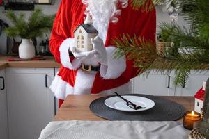 House key with keychain cottage in hands of Santa Claus outdoor in snow. Deal for real estate, purchase, construction, relocation, mortgage. Cozy home. Merry Christmas, new year booking event and hall photo