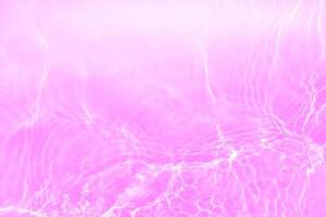 Defocus blurred transparent purple colored clear calm water surface texture with splashes and bubbles. Trendy abstract nature background. Water waves in sunlight with copy space. Pink water drop shine photo