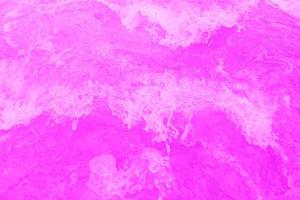 Defocus blurred transparent purple colored clear calm water surface texture with splashes and bubbles. Trendy abstract nature background. Water waves in sunlight with copy space. Pink water drop shine photo