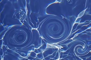 Defocus blurred transparent blue colored clear calm water surface texture with splashes and bubbles. Trendy abstract nature background. Water waves in sunlight with caustics. Blue water shinning photo