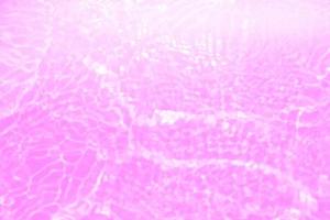 Defocus blurred transparent purple colored clear calm water surface texture with splashes and bubbles. Trendy abstract nature background. Water waves in sunlight with copy space. Pink water drop shine photo