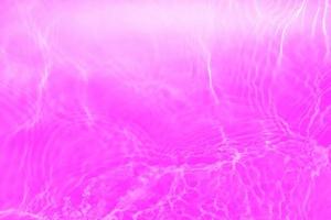 Defocus blurred transparent purple colored clear calm water surface texture with splashes and bubbles. Trendy abstract nature background. Water waves in sunlight with copy space. Pink water drop shine photo