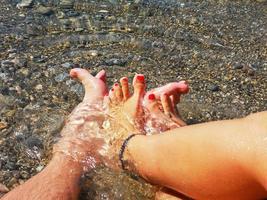 un par de pies cruzados en el agua del océano en una playa 1 foto