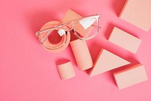 trendy eye glasses on geometric pink podiums, colorful background, copy space photo