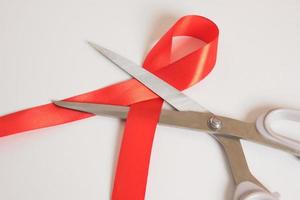 las tijeras son una cinta roja sobre el fondo gris. Día mundial del SIDA foto