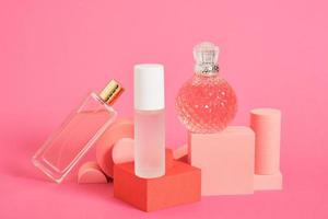 cristal glass perfume bottles and podiums on pink background copy space photo