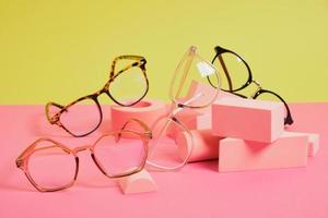 trendy eye glasses on geometric pink podiums, colorful background, copy space photo