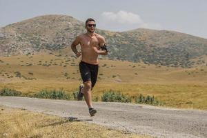 corredor de hombre deportivo corriendo en la meseta de la montaña en verano foto