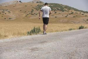 corredor de hombre deportivo corriendo en la meseta de la montaña en verano foto