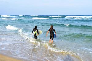 Surfers couple waiting for the high waves on beach - Sporty people with surf boards on the beach - Extreme sport and vacation concept photo