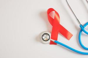 cinta roja y estetoscopio médico azul concepto de salud y sexo seguro. diciembre dia mundial del sida foto