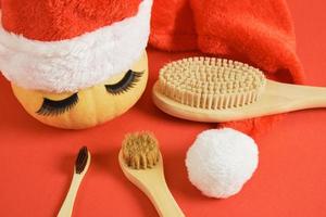 cepillo de dientes de bambú, cepillos de masaje de madera, calabaza con pestañas postizas y toalla sobre fondo gris foto