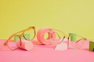 trendy eye glasses on geometric pink podiums, colorful background, copy space photo