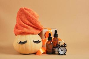 pumpkin with towel and false eyelashes, amber glass dropper bottles, gift box with ribbon and alarm clock photo