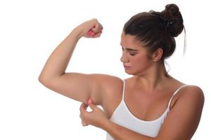 Woman pinching a fat on her arms on white background photo