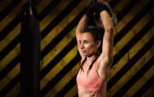 A female trainee of mixed martial arts warms up within the ring cage by stretching her back and legs. photo