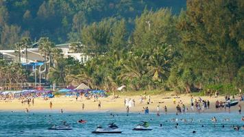 phuket, tailândia, 18 de novembro de 2017 - praia lotada com pessoas na praia. férias de verão, guarda-sóis para turistas, aquabikes na bela praia de areia em phuket, tailândia. video