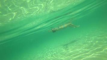 dispararle a una persona que flota bajo el agua. la niña yace sobre las olas del océano y disfruta del descanso video