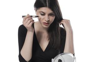 Portrait of a young woman applying liquid make up on her face. Isolated on white background photo