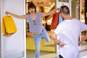 Portrait of cheerful Caucasian young couple man and woman holding many paper bags after shopping while walking and talking on street. Happy family couple with packages outdoor. Buying concept photo