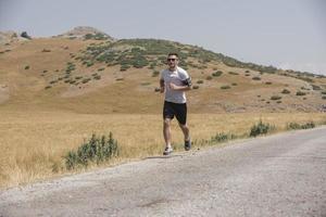 corredor de hombre deportivo corriendo en la meseta de la montaña en verano foto