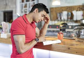 Handsome young man reading book at bar counter. photo