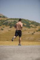 corredor de hombre deportivo corriendo en la meseta de la montaña en verano foto