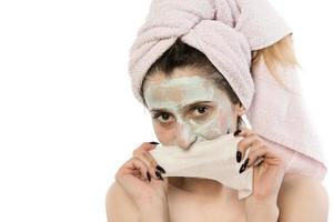 Beautiful woman having clay facial mask apply by beautician. photo