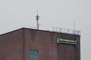 antenna on the roof of an brick industrial building photo