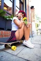 Beautiful hipster girl with skate board wearing sunglasses in the city. photo