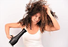 retrato de una hermosa chica alegre con el pelo rizado volando sonriendo riendo mirando a la cámara sobre fondo blanco. foto