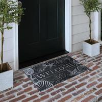 Designer Welcome Entry Doormat Placed on Solid Brick Floor Outside Entry Door with Plants photo