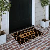 Designer Welcome Entry Doormat Placed on Solid Brick Floor Outside Entry Door with Plants photo