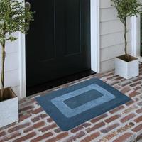 Designer Welcome Entry Doormat Placed on Solid Brick Floor Outside Entry Door with Plants photo