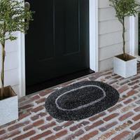 Designer Welcome Entry Doormat Placed on Solid Brick Floor Outside Entry Door with Plants photo