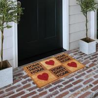 Designer Welcome Entry Doormat Placed on Solid Brick Floor Outside Entry Door with Plants photo