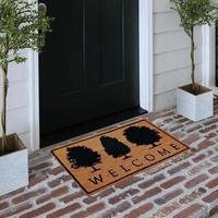 Designer Welcome Entry Doormat Placed on Solid Brick Floor Outside Entry Door with Plants photo