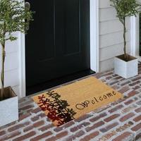 Designer Welcome Entry Doormat Placed on Solid Brick Floor Outside Entry Door with Plants photo